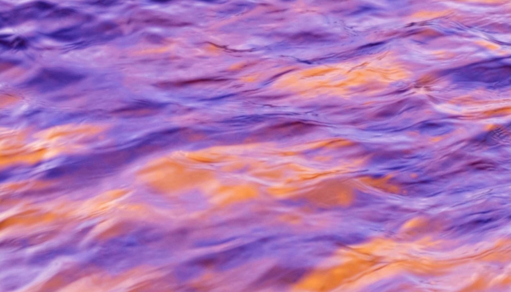 Soft abstract texture of flowing water with purple and orange tones blending together